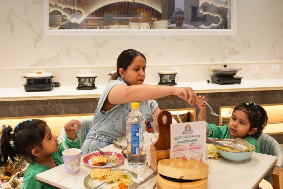 A mother serving her daughters, with the open kitchen visible behind