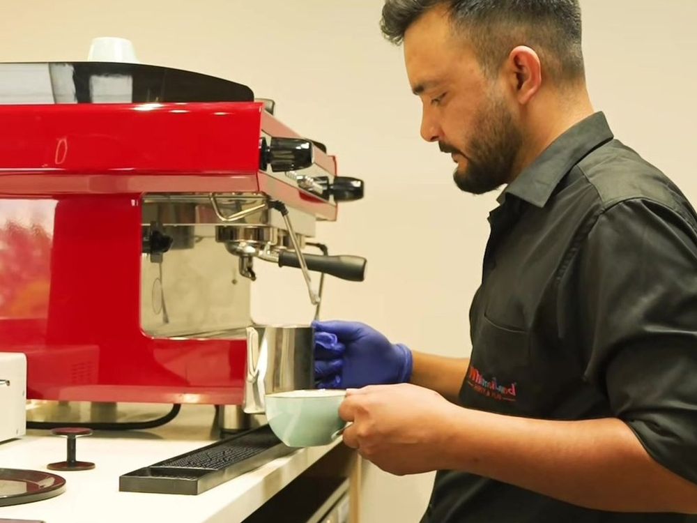 The WhimsiLand barista steaming milk at the espresso machine
