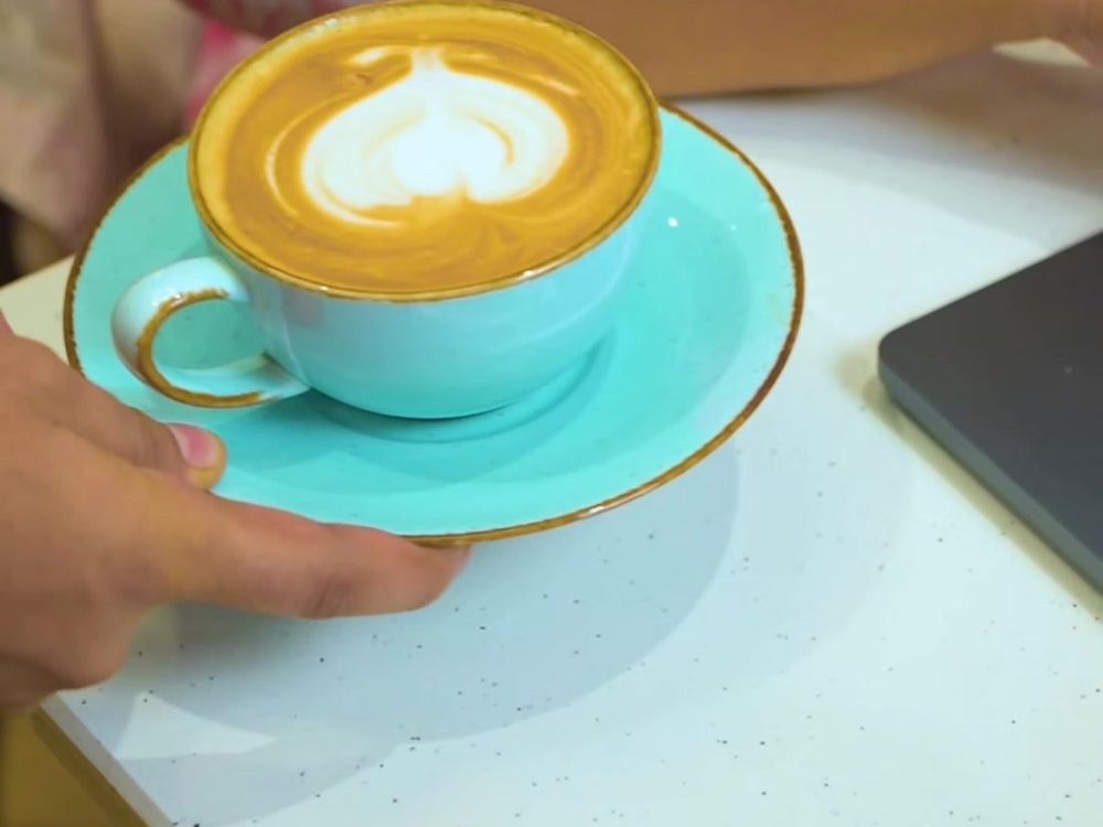 A cappuccino with heart latte art in a turquoise cup