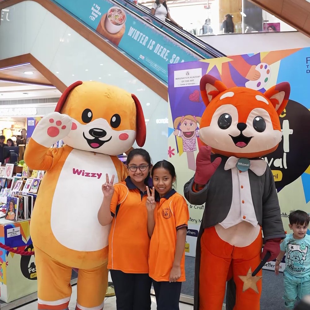 Whimsi and Wizzy posing with a group of children at a WhimsiLand event