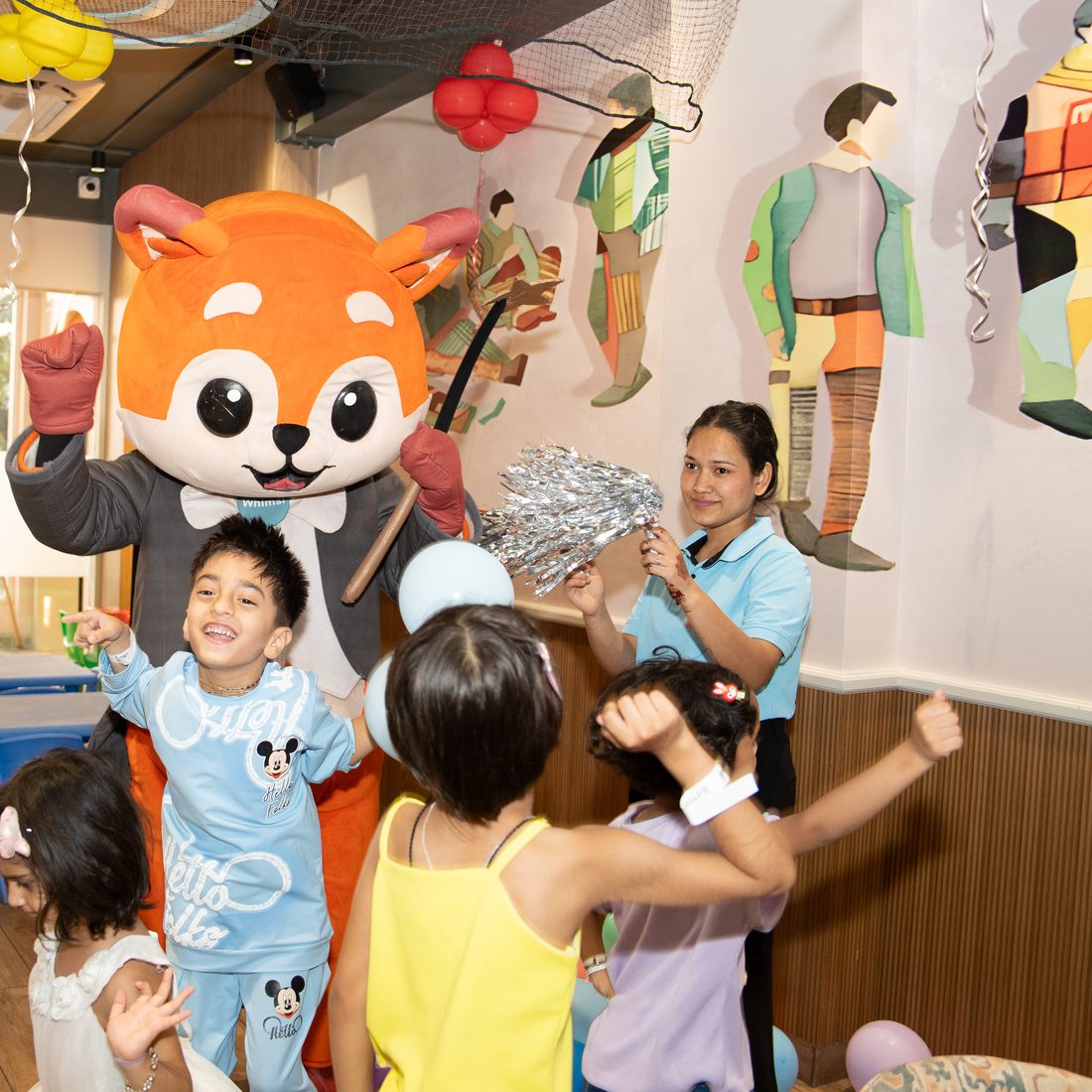 A boy cheering with his arms up while Whimsi dances behind him
